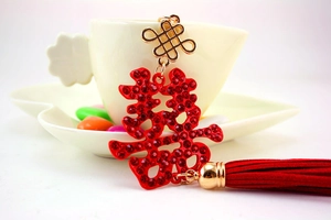 Macro detail of red rhinestone Double Happiness pendant with gold Chinese knot and tassel