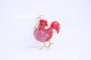 Close-up of sparkling rhinestone rooster keychain with red and pink crystals on gold metal