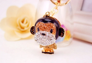Close-up of golden monkey keychain with white and amber rhinestones and black enamel