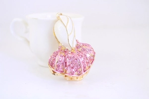 Dettaglio macro del ciondolo a cavolo con strass rosa e smalto bianco su anello d'oro