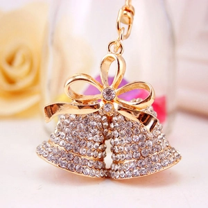 Sparkling white rhinestone double bell keychain with a golden bow on soft background