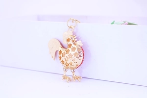 Detail of a golden rooster keychain featuring hollow patterns and sparkling rhinestones