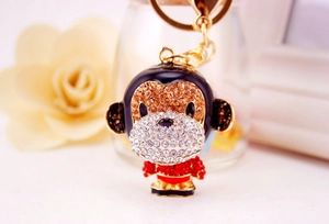 Macro view of gold monkey keychain featuring red and brown rhinestones on floral background
