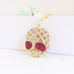 Pendentif porte-clés tête de mort doré orné de strass rouges et blancs brillants