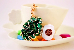 Close-up of golden Chinese cabbage keychain with green enamel and sparkling rhinestones