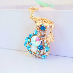 Golden money bag keychain with blue crystals and a small dollar sign charm on white background