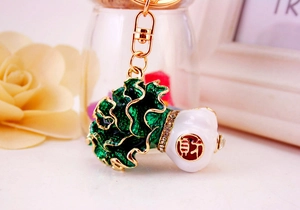 Detail of green enamel cabbage keychain with lucky charm engraving and crystal inlay