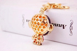 Detailed macro view of gold plated alloy astronaut keychain with hollow patterns and red rhinestones