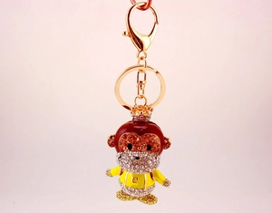 Detail of cartoon monkey keychain with gold alloy base and sparkling amber rhinestones