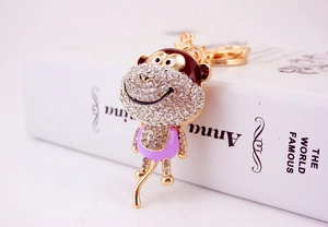 Close-up of cute cartoon monkey keychain with rhinestones and purple enamel detailing