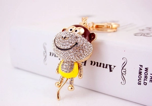 Close-up of golden rhinestone monkey keychain with yellow enamel shirt and lobster clasp