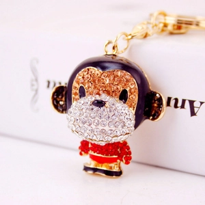 Exquisite golden monkey keychain with champagne and white rhinestones on a warm background