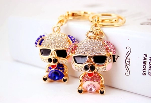 Close-up of pink and blue rhinestone pig keychains with sunglasses on a white book