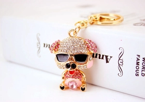Close-up of cute golden pig keychain with rhinestones and pink gemstone on a book