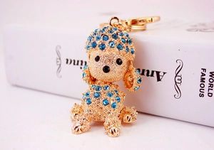 Detailed close-up of golden poodle keychain with blue crystals on a book edge