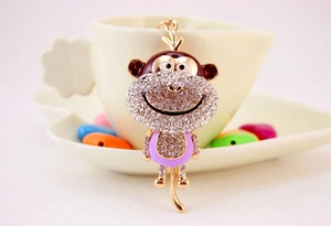 Detail of a sparkling rhinestone monkey keychain hanging on a cozy ceramic coffee cup