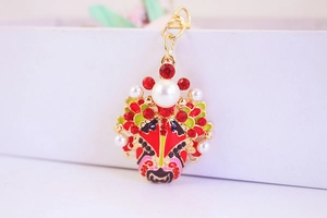 Macro detail of Beijing Opera mask keychain with gold metal plating and red rhinestones
