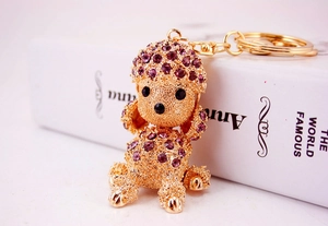 Detailed close-up of a golden metal poodle keychain decorated with sparkling purple rhinestones