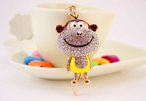 Close-up of a cartoon monkey keychain with rhinestones hanging on a coffee cup
