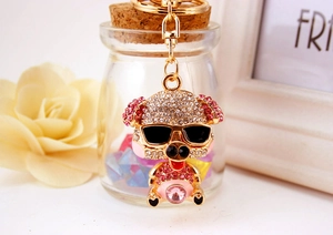 Detailed view of a gold pig keychain with pink rhinestones and black sunglasses
