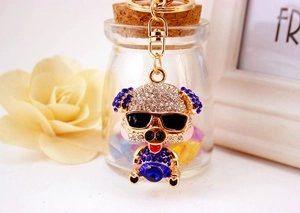 Detailed close-up of a golden rhinestone pig keychain with blue crystals and sunglasses