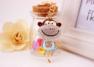 Close-up of golden alloy monkey keychain with white and brown rhinestones detail