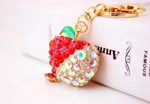 Close-up of red and rainbow rhinestones on apple keychain with gold metal frame