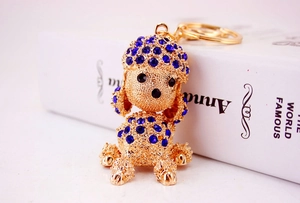 Close-up of golden poodle keychain with sparkling blue rhinestones on a book