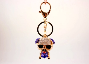 Detail view of a cute pig keychain with rhinestones and sunglasses on a golden metal base