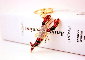 Détail d'un porte-clés homard avec strass et émail rouge sur un livre blanc élégant
