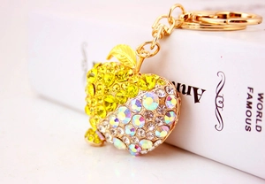 Detailed view of apple-shaped keychain with yellow and white rhinestones and gold plating