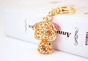 Detail of a golden dog keychain with heart cutouts and pink rhinestones on ears