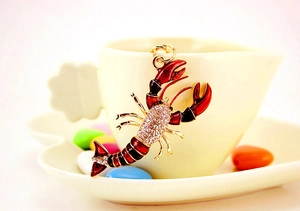 Détail d'un porte-clés homard rouge serti de cristaux sur une tasse blanche