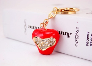 Macro view of red apple keychain with sparkling rhinestones and gold-plated chain links