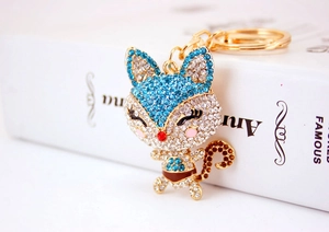 Close-up of golden cartoon fox keychain with sparkling sky blue and clear rhinestones