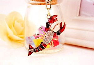 Détail d'un porte-clés homard en émail rouge avec strass et quincaillerie dorée