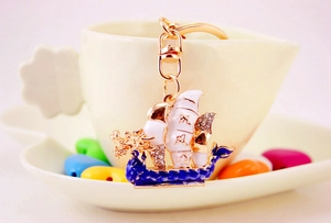 Dettaglio portachiavi barca drago con smalto blu e strass su una tazza da caffè
