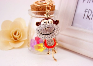 Detailed close-up of a sparkling rhinestone monkey keychain with a long tail on gold metal