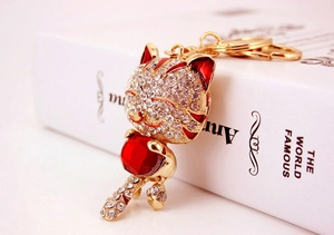 Gros plan d'un porte-clés chat porte-bonheur doré avec strass et gemme en forme de cœur