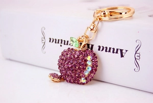 Detailed view of apple keychain with purple rhinestones on a white book prop
