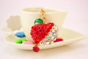 Close-up of apple keychain with red and aurora borealis crystals hanging on a cup