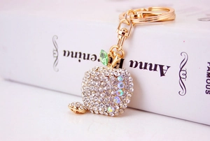 Close-up of sparkling crystal-encrusted apple keychain with golden lobster clasp and leaf