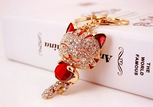 Détail du porte-clés chat doré avec strass blancs brillants et une pierre rouge