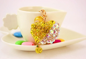 Detailed macro view of a golden apple keychain featuring yellow and multi-colored rhinestones