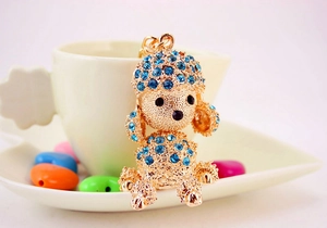 Close-up of golden poodle keychain featuring sparkling blue rhinestones and black gem eyes