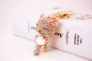 Détail d'un porte-clés chat doré avec une gemme rose et des strass étincelants
