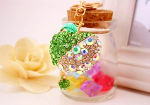 Macro detail of apple keychain with green rhinestones and golden metal lobster clasp