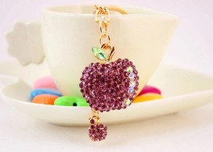 Detail of purple rhinestone apple keychain with gold metal plating and green leaf accent