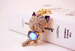 Détail d'un porte-clés chat chanceux avec émail violet et un grand cristal bleu