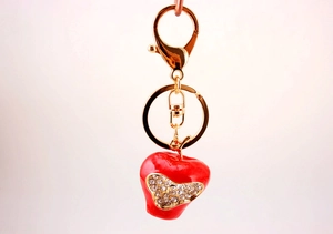 Detailed view of a red apple keychain with sparkling heart-shaped rhinestones and gold clasp